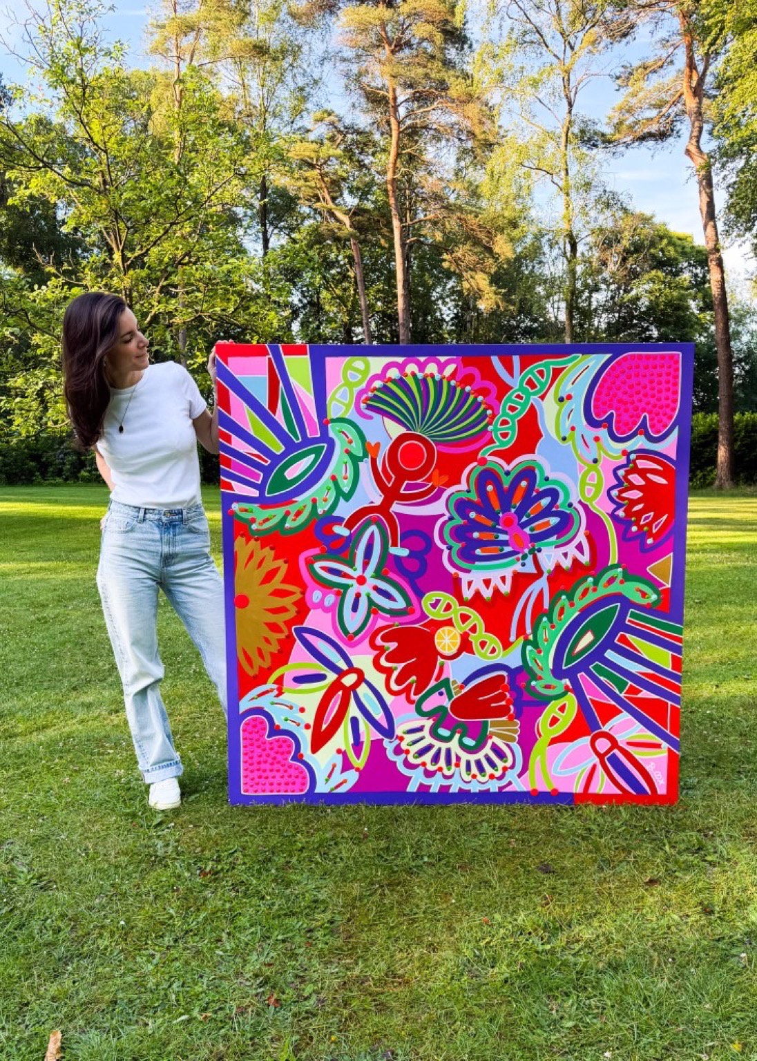 Barbara Cox holding one of her large paintings outdoors