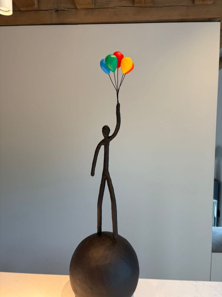 Grégoire Vanderstappen sculpture — dark bronze figure with heart-shaped balloons on a sphere
