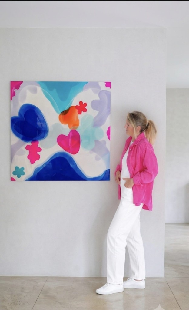 Artist Valérie Parmentier beside one of her colourful resin heart-and-flower paintings